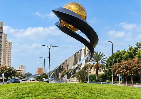 סרט פלדה שחור המתפתל סביב כדור זהוב, מעל בסיס נירוסטה מלוטש